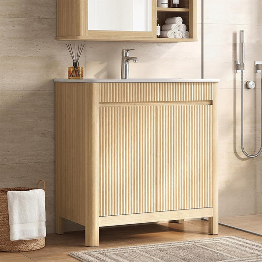 Freestanding light wood-tone bathroom vanity with a fluted front, rounded legs and white sink beside a shower