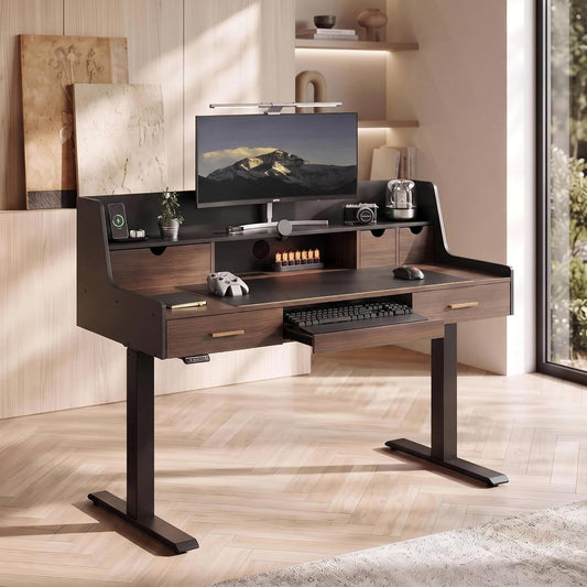 Dark brown desk with drawers, raised storage shelves and a pull-out keyboard tray holds a monitor, mouse, game controller, camera and small plant beside a large window.