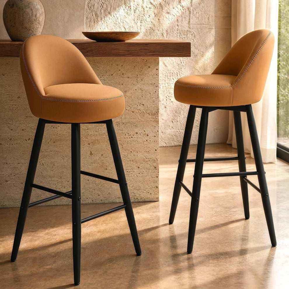 Two tan upholstered stools with curved backs and dark footrest frames stand beside a counter