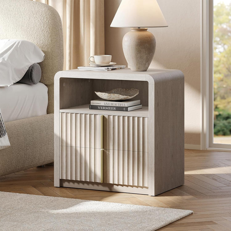 Whitewashed nightstand with two fluted drawers, an open cubby and rounded upper corners beside a bed
