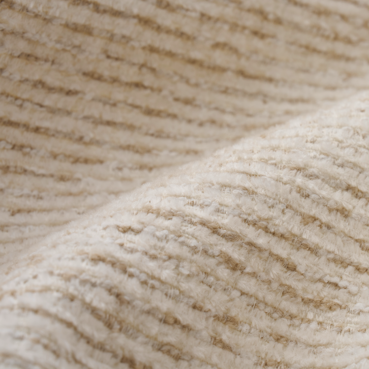 Close-up of a cream-colored fuzzy textile with dense, wavy fibers and ridged rows.