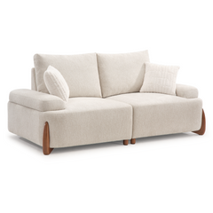 A light beige two-seat sofa with two back cushions, two white throw pillows, broad arms, and curved brown legs, shown against a white background.