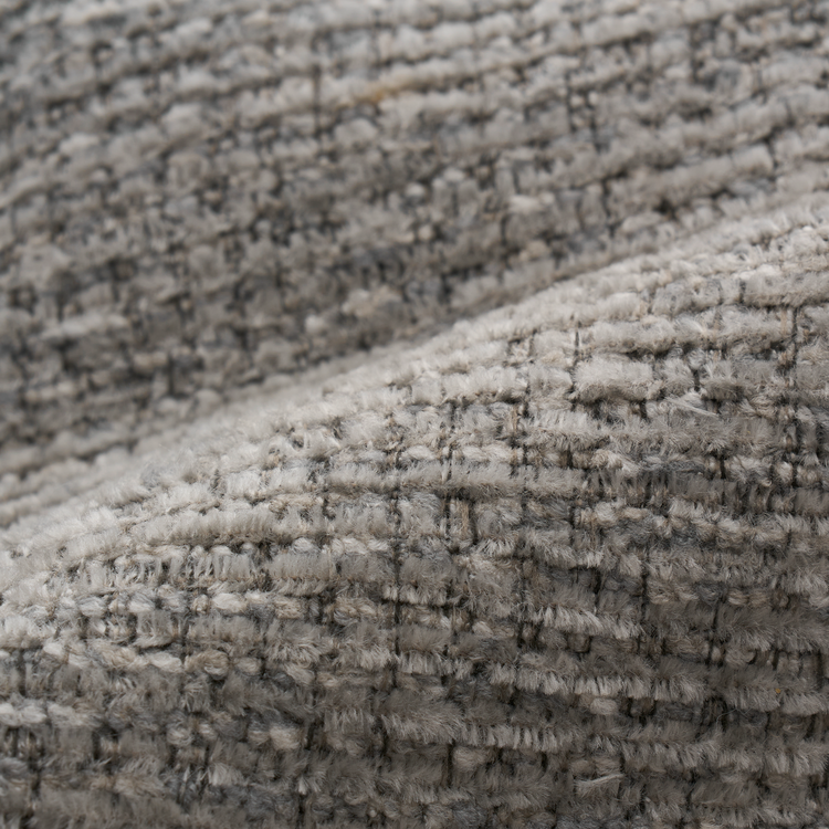 Close-up of a fuzzy, looped gray-beige woven textile with rows of raised stitching.