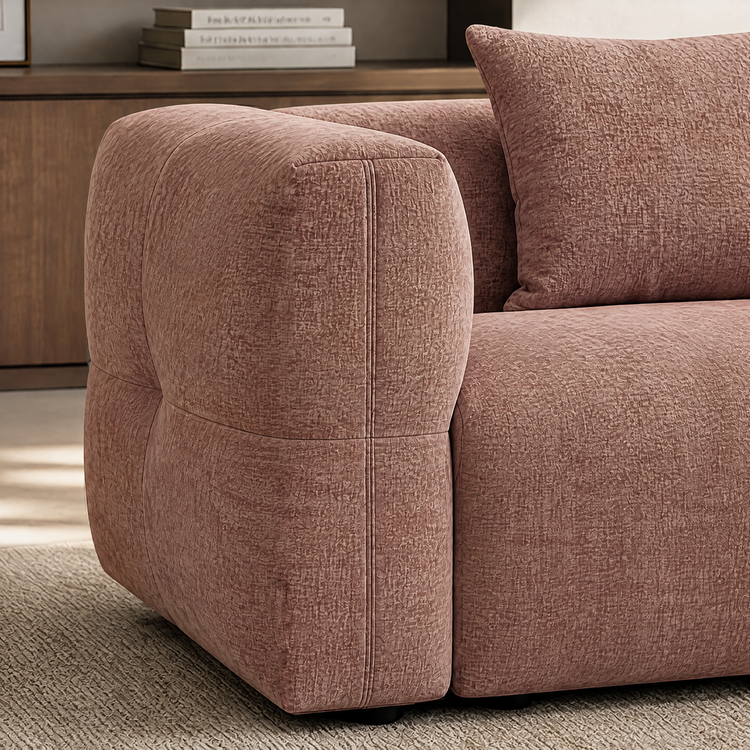 Close-up of a dusty pink upholstered sofa with rounded arm and textured fabric.