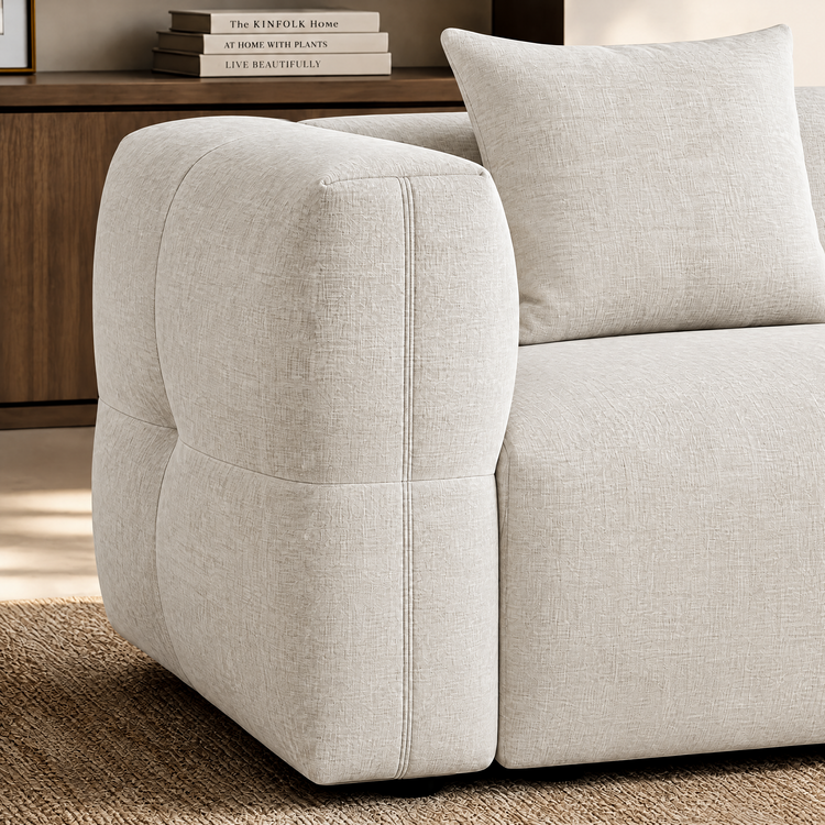 Close-up of ivory upholstered seating with a rounded arm and matching cushion.