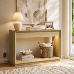 Light wood console table with open lower space, lamp, books, and basket in a bright room