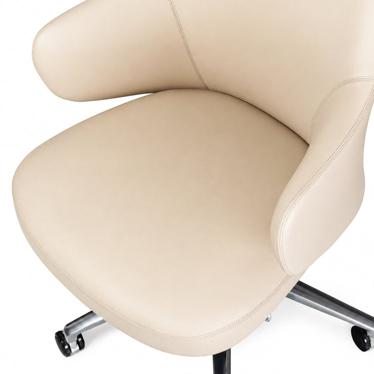 Close-up of a cream upholstered chair with a curved seat and back, stitched seams, padded armrests, and a metal wheeled base.