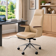 Beige high-back office chair with dark brown armrest tops and a shiny five-spoke wheeled base beside a desk in a sunlit room.