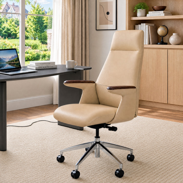 Beige high-back office chair with dark brown armrest tops and a shiny five-spoke wheeled base beside a desk in a sunlit room.