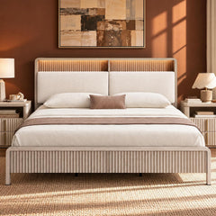 Cream bed with a vertically ridged frame and padded headboard, white bedding and brown accents, flanked by bedside tables and lamps beneath an abstract painting.
