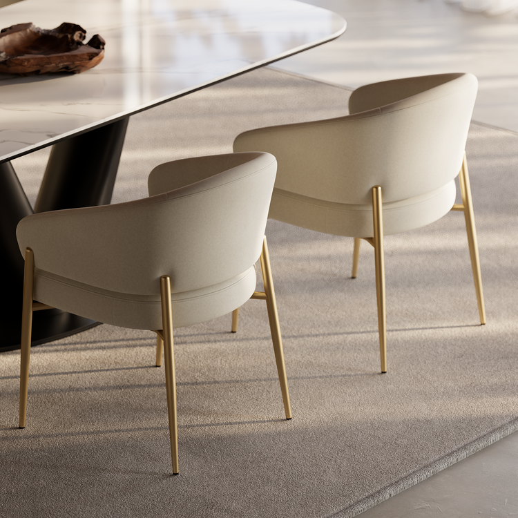 Two cream upholstered dining chairs with gold-tone legs beside a modern table