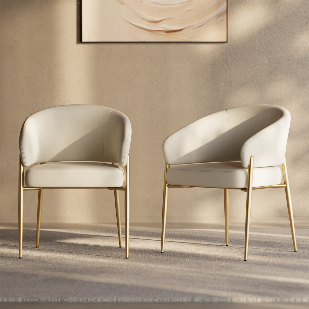 Two cream upholstered accent chairs with curved backs and gold-tone metal legs.