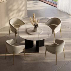Round marble-look dining table with four beige chairs in a sunlit room.