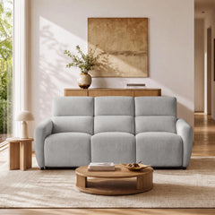 Light gray three-seat sofa with tall padded backs and rounded arms behind a low round coffee table