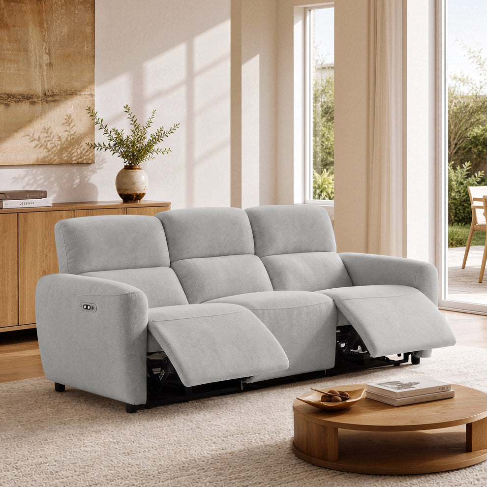 Gray three-seat reclining sofa with both outer footrests extended in a bright living room