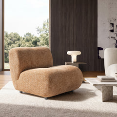 An armless lounge chair has a wide rounded seat, curved back, textured upholstery, and short cylindrical feet