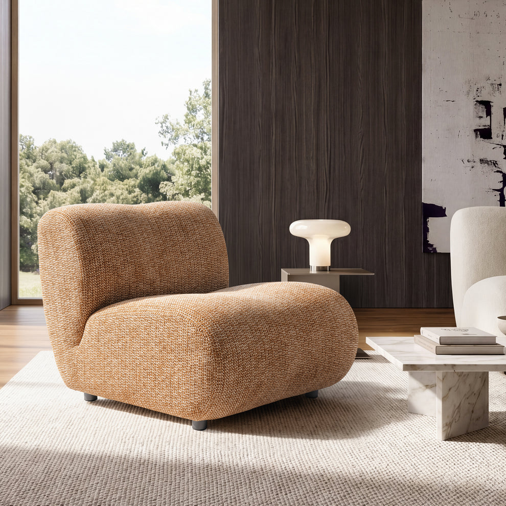 An armless lounge chair has a wide rounded seat, curved back, textured upholstery, and short cylindrical feet