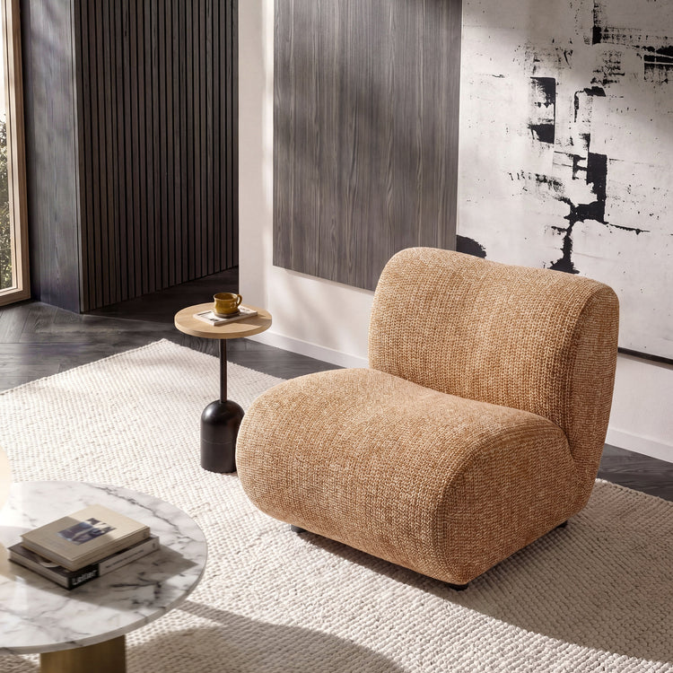 Rounded tan lounge chair sits on a pale rug in a modern room