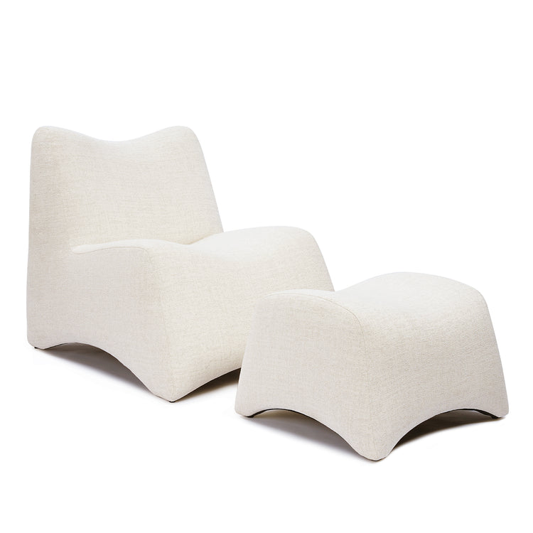 The cream lounge chair has a continuous curved profile and is shown with a matching curved footstool