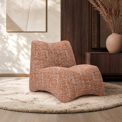 Rust-and-cream patterned lounge chair sits on a shag rug in a wood-paneled room