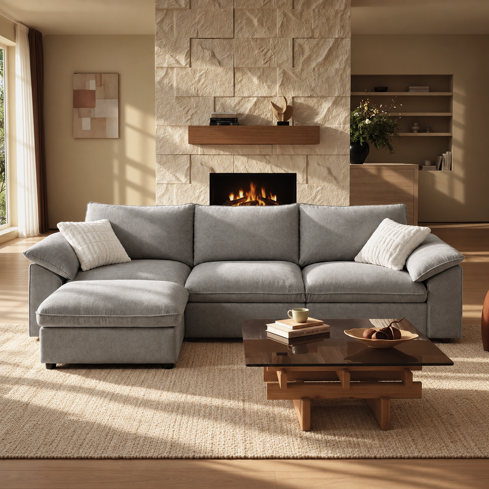 Gray L-shaped sofa with matching ottoman and white pillows in a sunlit living room