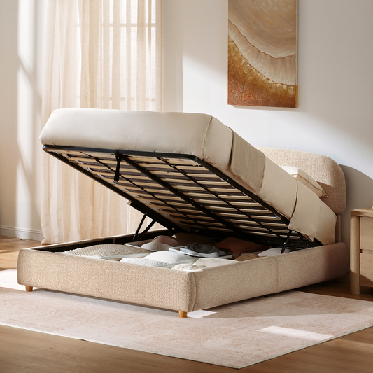 Textured upholstered storage bed with its mattress platform raised above compartments containing pillows and folded blankets