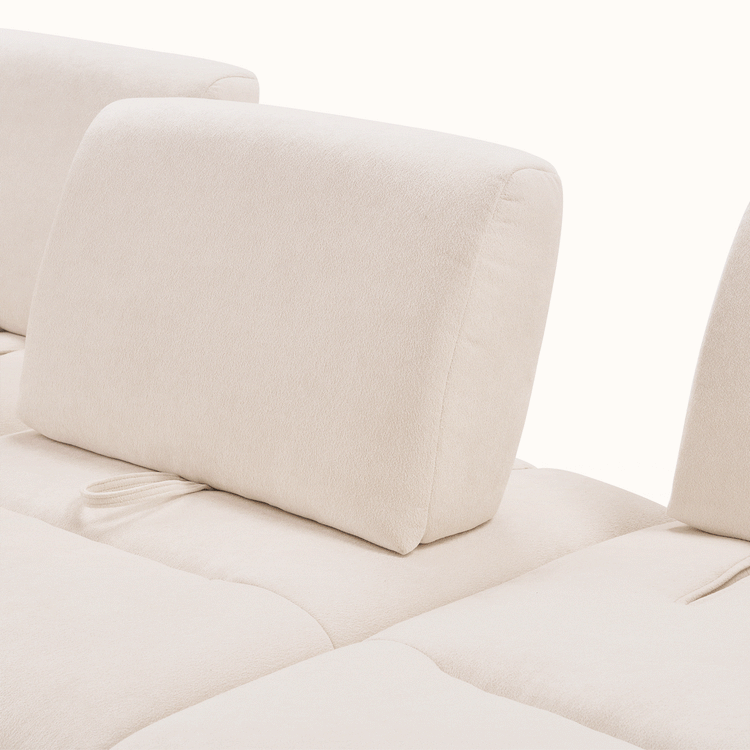 Close-up of cream upholstered sofa cushions with rounded backrests and stitched seams.