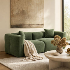 Green modular sectional sofa with matching cushions in a sunlit living room.