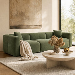Green sectional sofa with a chaise in a sunlit living room.