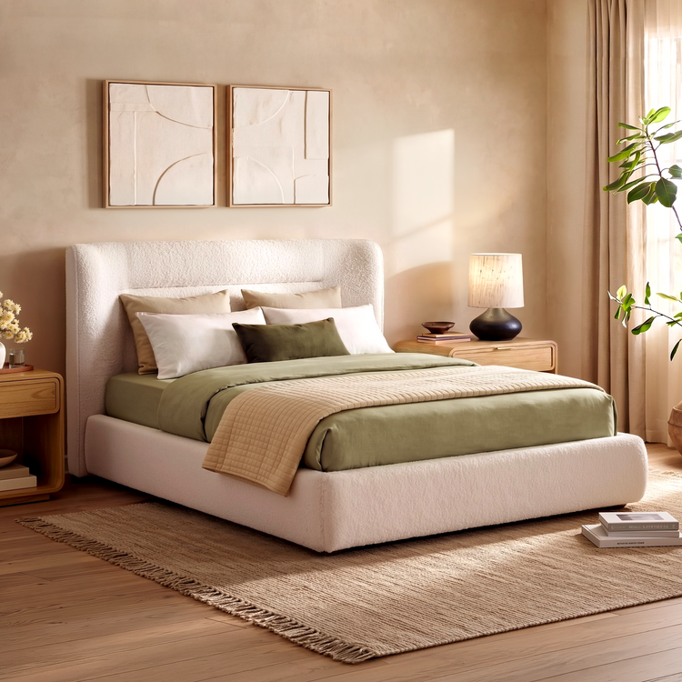 Cream upholstered bed with beige and green bedding in a bright neutral bedroom