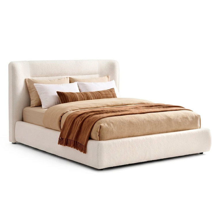 The bed has a tall rounded headboard, Layered bedding and pillows cover the bed