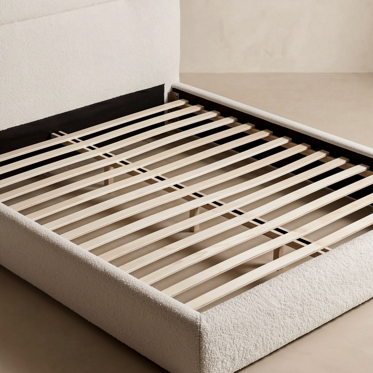 Upholstered bed frame is shown without a mattress, exposing parallel support slats, Cross supports are visible beneath the slats