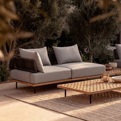 A two-seat outdoor sofa with open woven side panels is centered in the scene