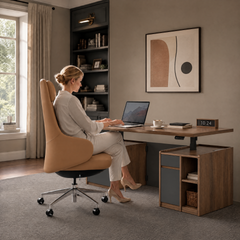 A woman sits in a tan high-backed swivel chair using a laptop at a brown desk with storage cabinets, a cup, books and a digital clock in a home office.