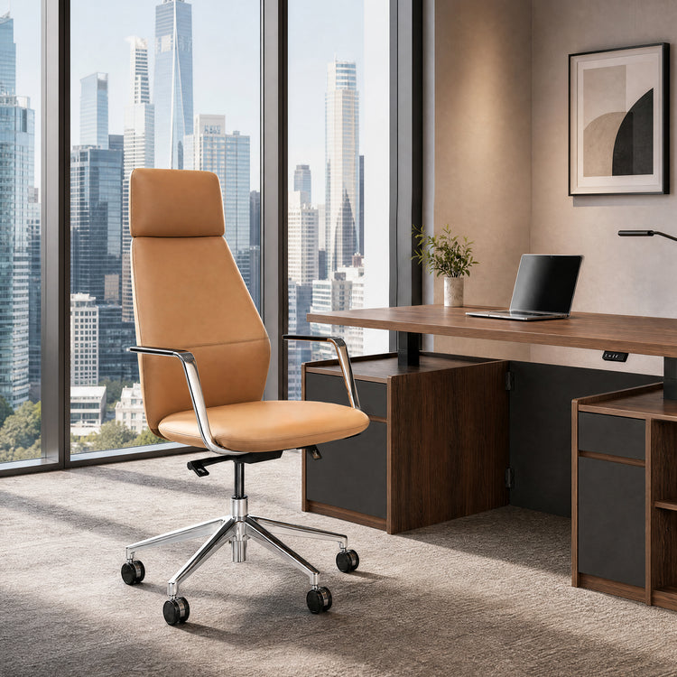 Tan high-back office chair with silver-colored armrests and a wheeled base beside a brown desk with a laptop, overlooking city buildings through tall windows.