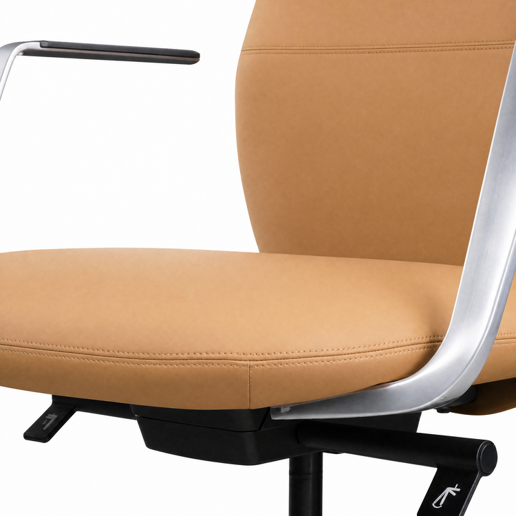 Close-up of a tan upholstered chair with stitched seams, curved silver arm supports, black armrests, and a black adjustment lever against a white background.