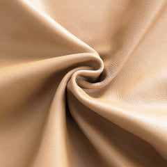 Close-up of a tan, finely pebbled surface gathered into curved folds around a central swirl.