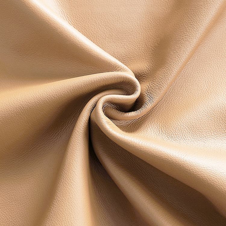 Close-up of a tan, finely pebbled surface gathered into curved folds around a central swirl.