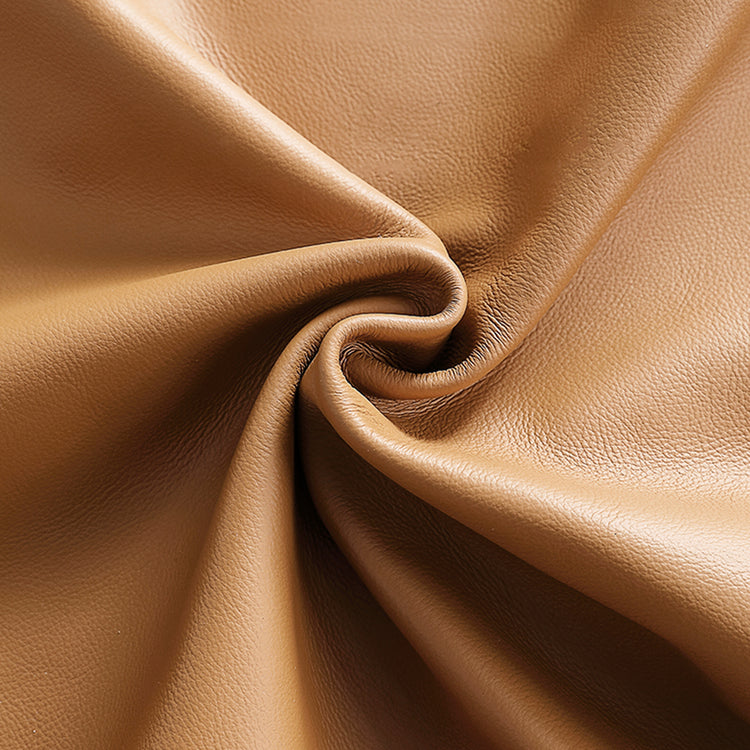 Close-up of a tan, finely grained surface gathered into curved folds around a central twist.