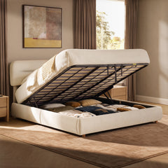 Cream upholstered bed with its mattress and slatted base lifted to reveal a storage compartment filled with cushions and folded bedding.