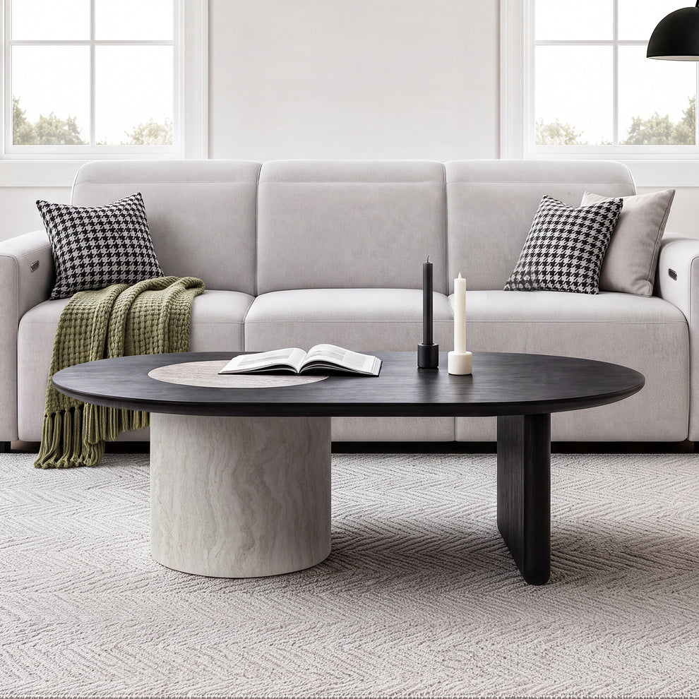 Dark oval coffee table with a pale circular inset and contrasting cylindrical support in front of a white sofa