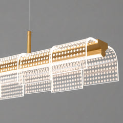 Close-up of a suspended light with a gold-colored horizontal bar and overlapping curved transparent panels patterned with rows of glowing white dots.