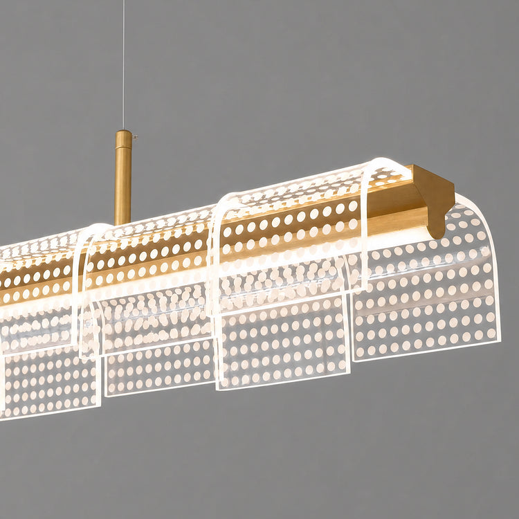 Close-up of a suspended light with a gold-colored horizontal bar and overlapping curved transparent panels patterned with rows of glowing white dots.