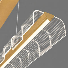 Close-up of a suspended light with a gold-colored central bar, a glowing strip, and curved clear panels patterned with white dots against a gray background.