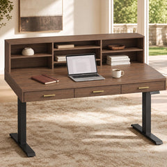 A dark wood desk with three drawers and an upper shelving unit holds a laptop, notebook, cup, books, and small decor in a sunlit room.