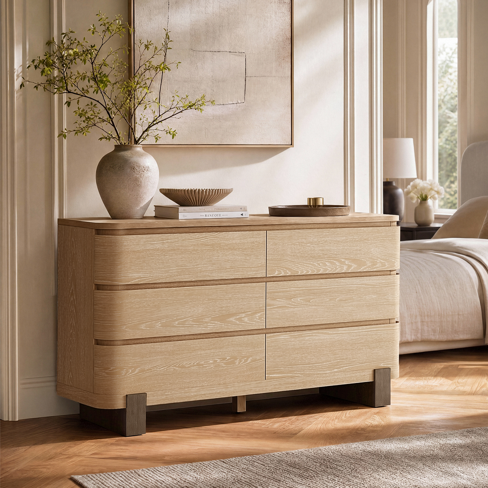 Light wood-toned dresser beside a bed in a bright bedroom