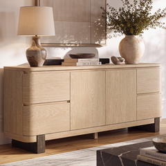 Light wood-toned sideboard has four drawers, two central doors, rounded corners, and dark block legs