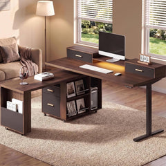A dark wood L-shaped desk with drawers and shelves holds a monitor, keyboard, mouse, and headphones in a sunlit room.