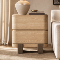 The cabinet has two stacked drawers with broad curved fronts, Four short block feet support the cabinet