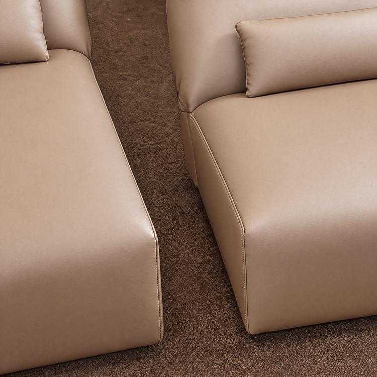 Close-up of two beige upholstered sofa sections with stitched seams and cushions.